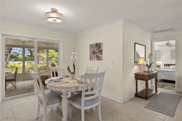 tiled dining space with ceiling fan and ornamental molding