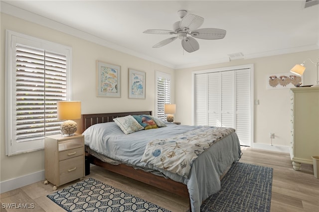 bedroom with light hardwood / wood-style flooring, a closet, ornamental molding, and ceiling fan