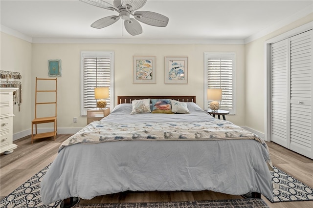 bedroom featuring light wood-type flooring, a closet, ceiling fan, and crown molding