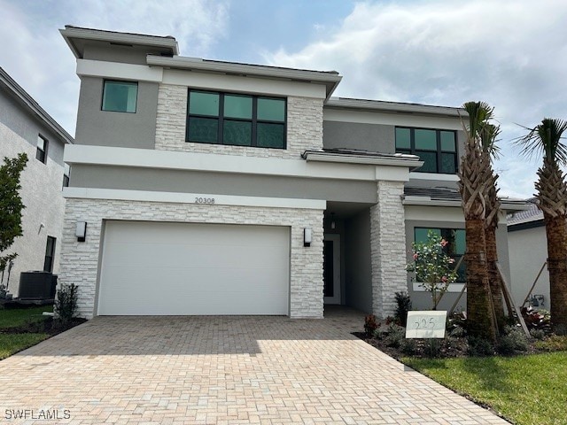 view of front of property with a garage and central air condition unit