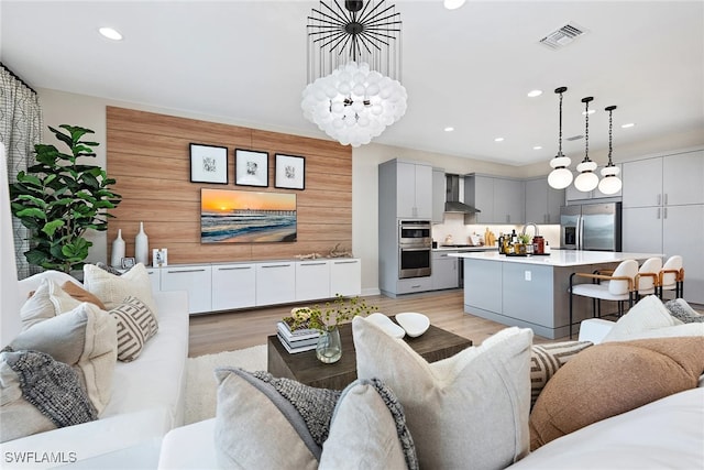 living room with sink, light hardwood / wood-style floors, and an inviting chandelier