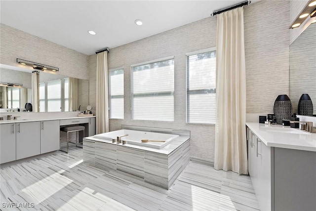 bathroom with vanity, a relaxing tiled tub, and tile walls