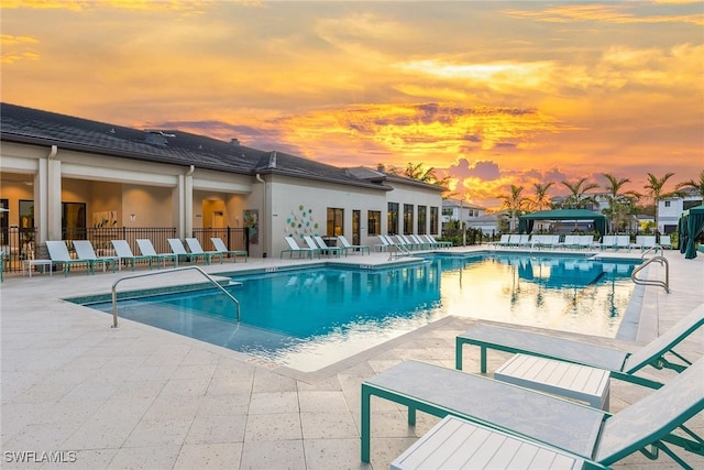 pool at dusk featuring a patio area