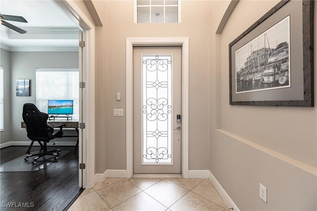 tiled entrance foyer with ceiling fan and ornamental molding