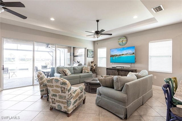 living room featuring ceiling fan, light tile patterned flooring, and a tray ceiling