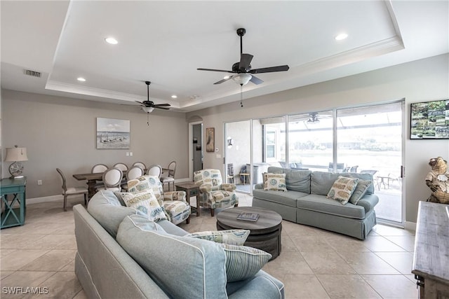 living room featuring light tile patterned floors, ceiling fan, and a tray ceiling