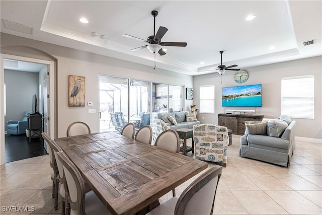 tiled dining space featuring a tray ceiling, ceiling fan, and ornamental molding