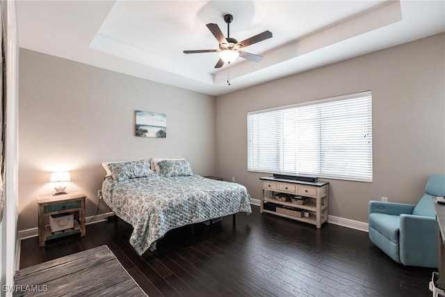 bedroom featuring ceiling fan, dark hardwood / wood-style floors, and a raised ceiling