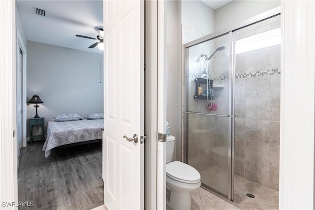 bathroom featuring ceiling fan, a shower with door, wood-type flooring, and toilet