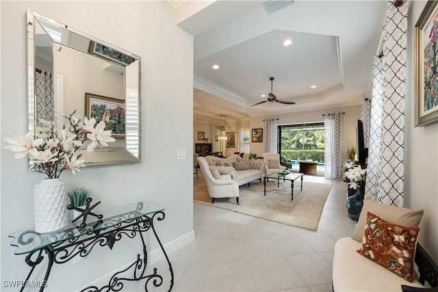 living room featuring ceiling fan, light tile patterned floors, crown molding, and a raised ceiling