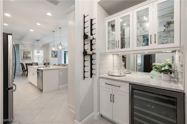 bar with tasteful backsplash, wine cooler, hanging light fixtures, white cabinets, and sink