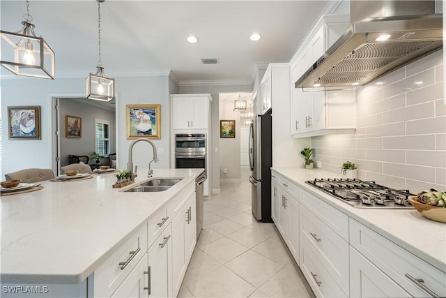 kitchen featuring sink, wall chimney range hood, white cabinetry, and pendant lighting