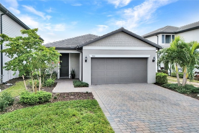 view of front of property featuring decorative driveway, a tile roof, an attached garage, and stucco siding