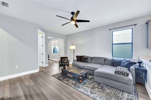 living area featuring visible vents, baseboards, wood finished floors, and a ceiling fan