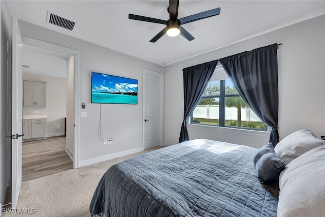 bedroom featuring visible vents, baseboards, light colored carpet, and a ceiling fan