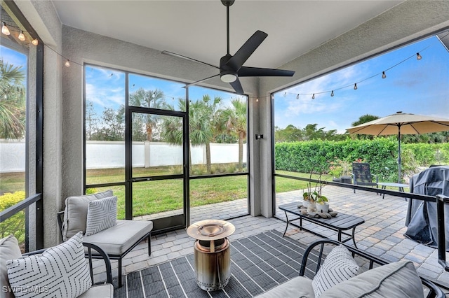 sunroom / solarium with a water view, a wealth of natural light, and ceiling fan