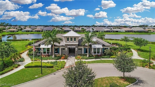 view of front facade featuring a residential view, curved driveway, and a water view