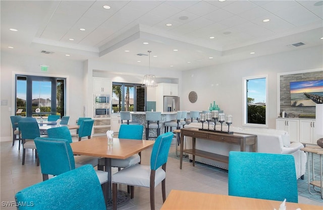 dining space with a tray ceiling, crown molding, and visible vents