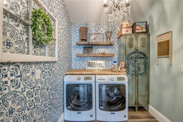 laundry room with washing machine and clothes dryer, a chandelier, and wood-type flooring