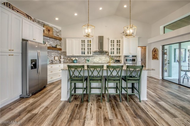 kitchen with backsplash, white cabinets, stainless steel appliances, and wall chimney range hood