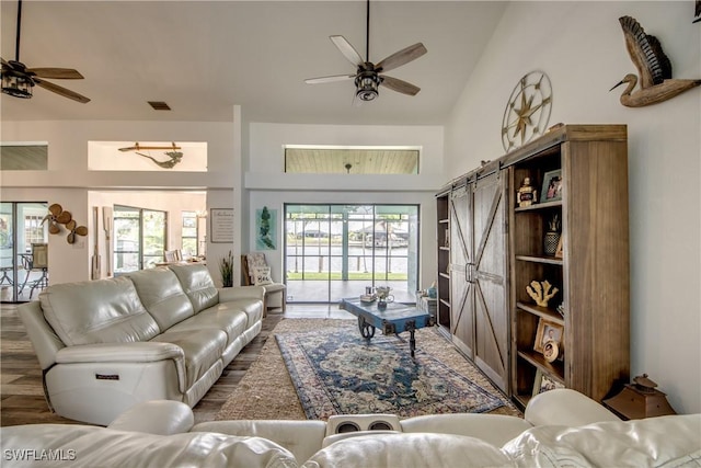 living room featuring a barn door, ceiling fan, hardwood / wood-style floors, and lofted ceiling