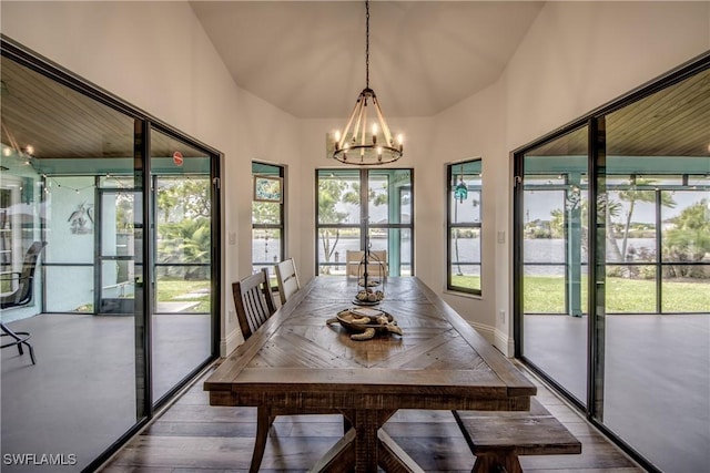 unfurnished dining area with lofted ceiling, wood-type flooring, and an inviting chandelier