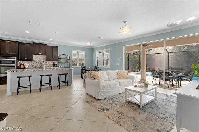 living room featuring light tile patterned flooring, ornamental molding, and sink