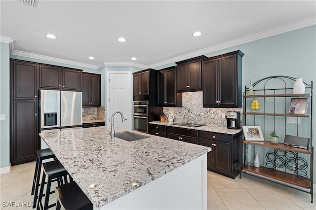 kitchen with backsplash, ornamental molding, sink, and an island with sink