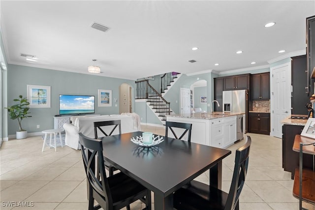 dining area with sink, ornamental molding, and light tile patterned flooring