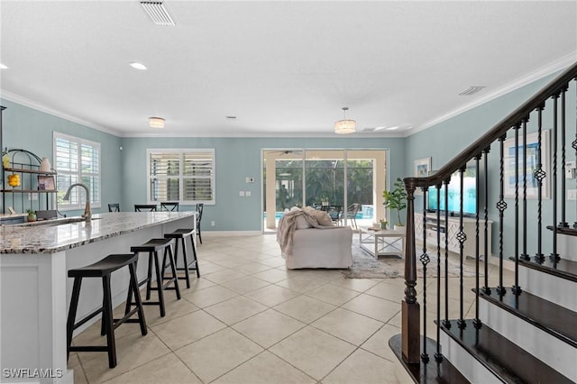 living room with light tile patterned flooring, ornamental molding, and sink