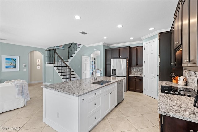 kitchen featuring sink, white cabinetry, light tile patterned floors, light stone countertops, and a kitchen island with sink