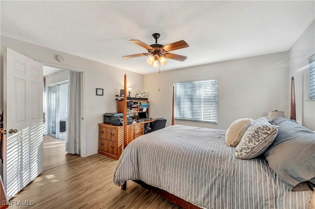 bedroom with access to outside, ceiling fan, wood-type flooring, and a textured ceiling