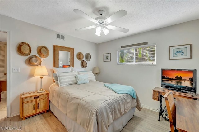 bedroom with a textured ceiling, light hardwood / wood-style floors, and ceiling fan