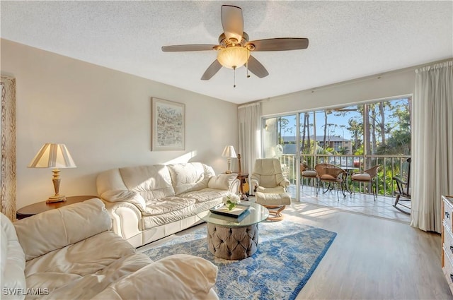 living room featuring ceiling fan, a textured ceiling, and a wealth of natural light