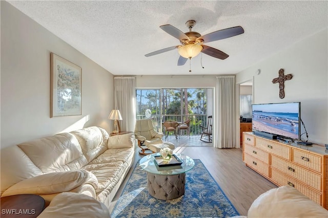 living room featuring ceiling fan, a textured ceiling, and light wood-type flooring