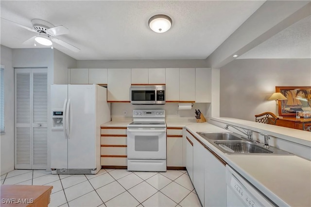 kitchen with white cabinets, light tile patterned flooring, white appliances, and sink