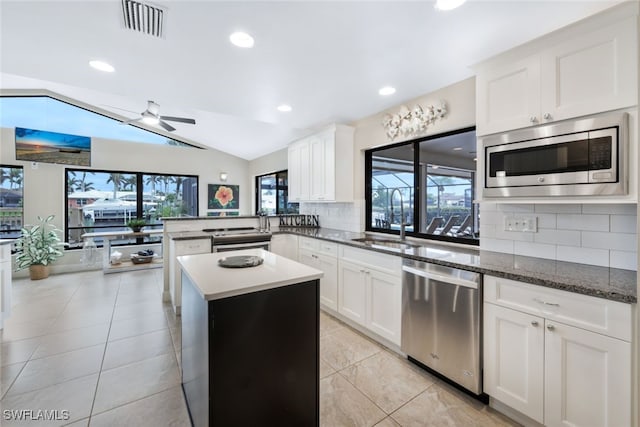 kitchen featuring decorative backsplash, stainless steel appliances, sink, white cabinets, and lofted ceiling