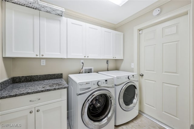 washroom with cabinets, ornamental molding, and washing machine and clothes dryer