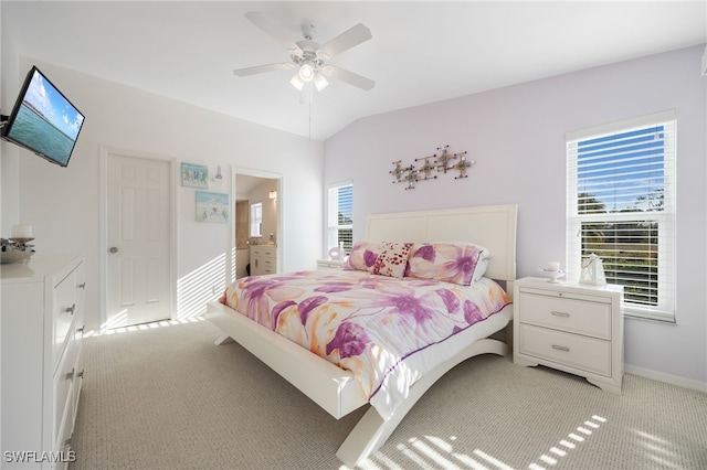 carpeted bedroom with multiple windows, ensuite bath, lofted ceiling, and ceiling fan