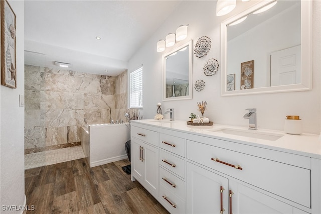 bathroom featuring wood-type flooring, a tile shower, and vanity