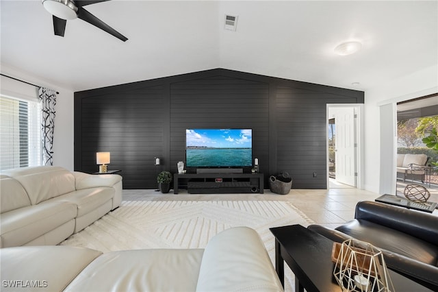 living room featuring vaulted ceiling, wood walls, ceiling fan, and light tile patterned flooring