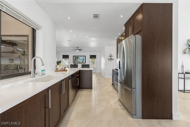 kitchen with kitchen peninsula, sink, ceiling fan, dark brown cabinetry, and stainless steel appliances