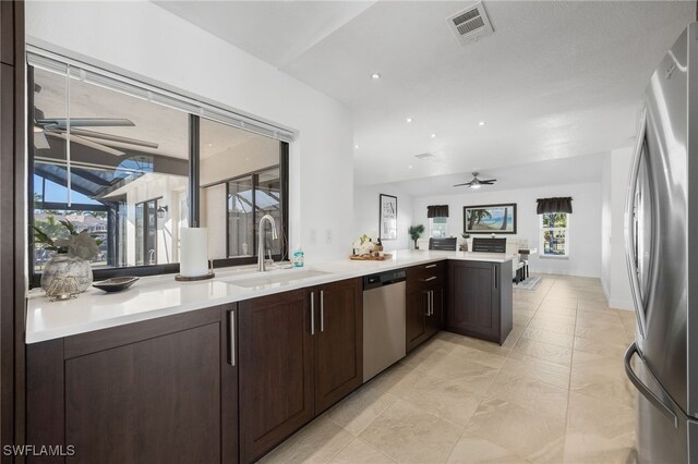 kitchen with stainless steel appliances, sink, dark brown cabinetry, and ceiling fan