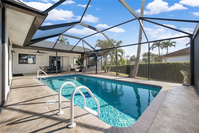 view of pool with a patio area, ceiling fan, and glass enclosure