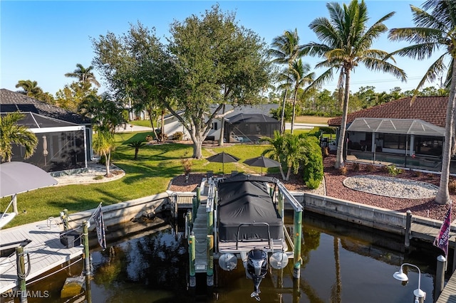 view of dock with a water view, glass enclosure, and a lawn