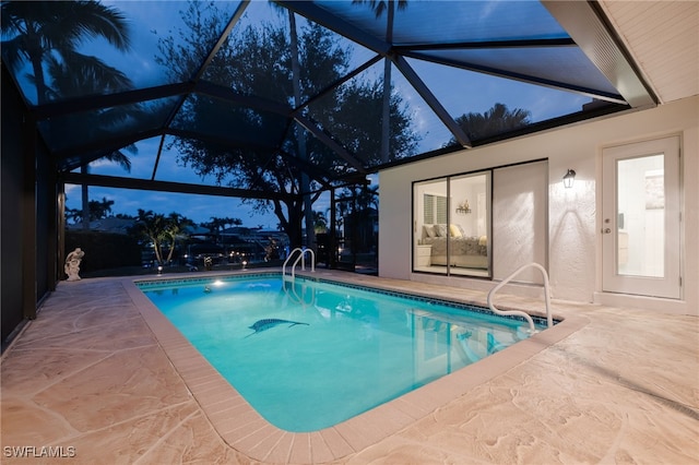 pool at dusk with a lanai and a patio