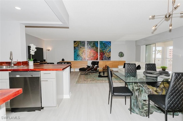 dining space featuring sink, light hardwood / wood-style floors, and a notable chandelier