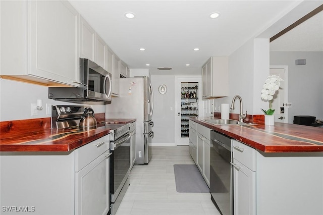 kitchen featuring stainless steel appliances, white cabinetry, and sink