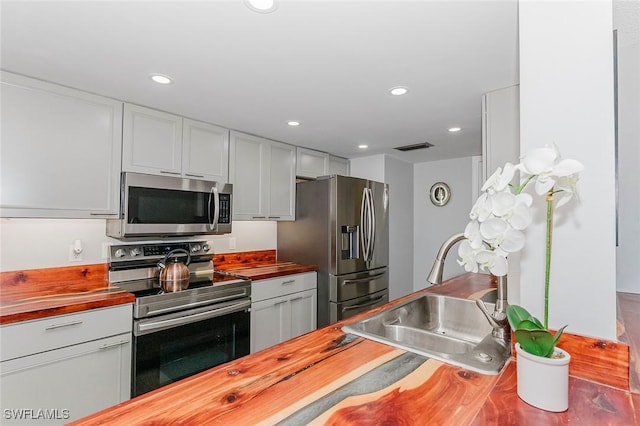 kitchen with wood counters, sink, and appliances with stainless steel finishes