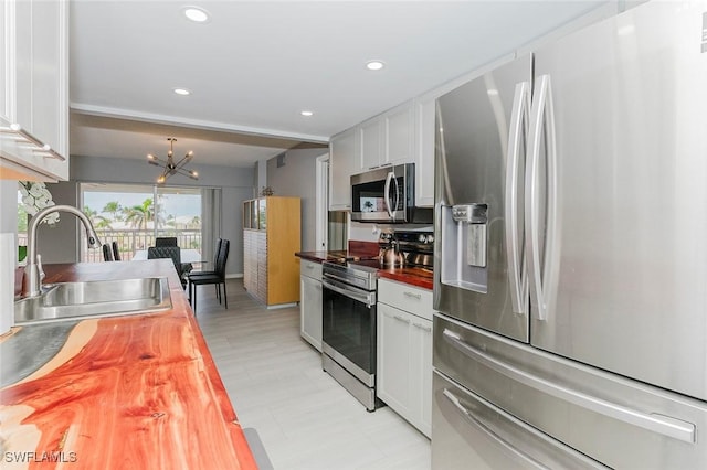 kitchen with white cabinets, stainless steel appliances, butcher block countertops, and sink